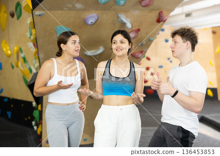 Asian girl, European woman and teenage guy - group of friends stand actively relaxing in climb hall Asian girl, European woman and teenage guy - group of friends stand actively relaxing in climb hall 136453853