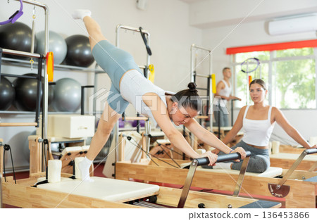 Young woman doing stretching on pilates machine 136453866
