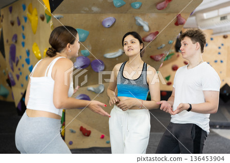 Two young women and teen boy talking at climbing wall 136453904