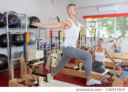 Young man doing stretching on pilates machine Young man doing stretching on pilates machine 136453924