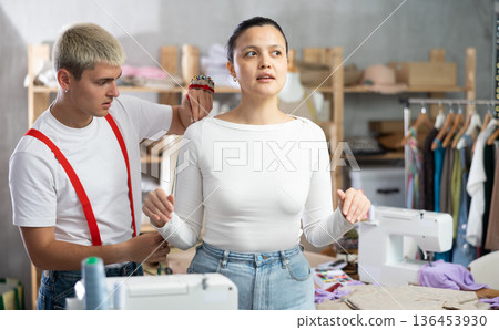 Professional qualified male dressmaker taking measurements of woman client for tailoring in sewing workshop Professional qualified male dressmaker taking measurements of woman client for tailoring in sewing workshop 136453930