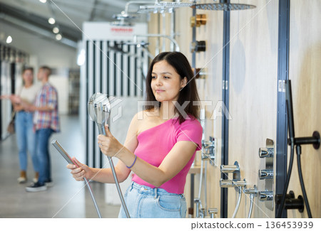 Young girl choosing a shower head in hardware store Young girl choosing a shower head in hardware store 136453939