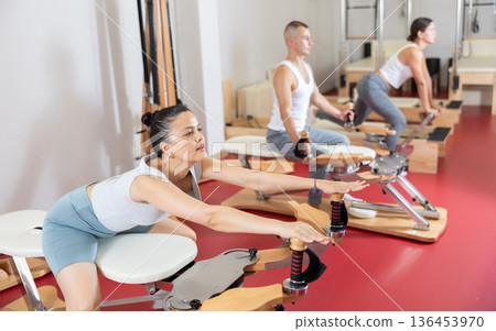 Sportive young girl training her arms turning handle of exercise machine 136453970