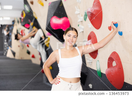 Young woman posing against climbing wall 136453973