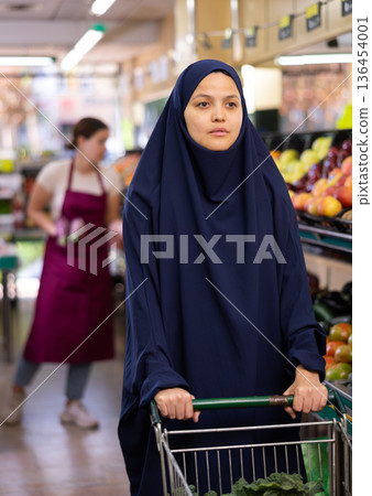 Woman in paranja with shopping cart in supermarket Woman in paranja with shopping cart in supermarket 136454001