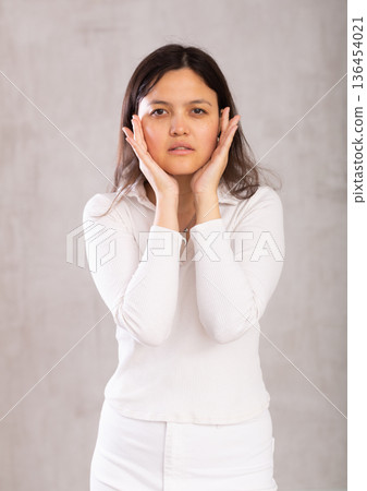Studio portrait of pretty young Asian girl in a white trouser suit on gray background Studio portrait of pretty young Asian girl in a white trouser suit on gray background 136454021