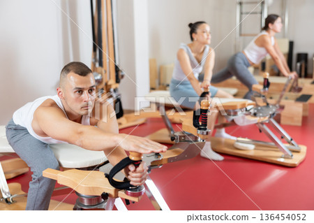 Sportive young guy training her arms turning handle of exercise machine 136454052