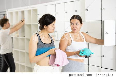 Two athletic girls have a conversation in gym locker room Two athletic girls have a conversation in gym locker room 136454183