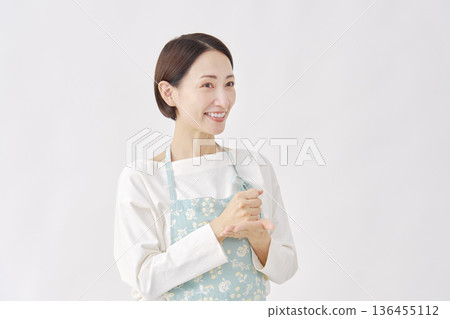 A woman wearing an apron is convinced, white background A woman wearing an apron is convinced, white background 136455112