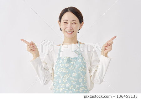 Woman wearing an apron pointing left and right, white background Woman wearing an apron pointing left and right, white background 136455135