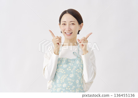 Woman wearing an apron pointing left and right, white background Woman wearing an apron pointing left and right, white background 136455136