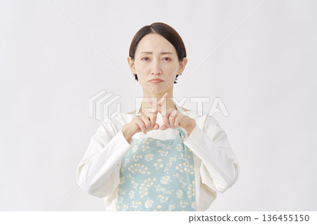 Woman wearing an apron making a cross gesture on a white background 136455150