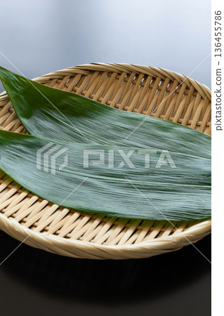 Bamboo leaves and a strainer on a black background Food background material 136455786