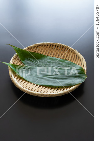 Bamboo leaves and a strainer on a black background Food background material 136455787