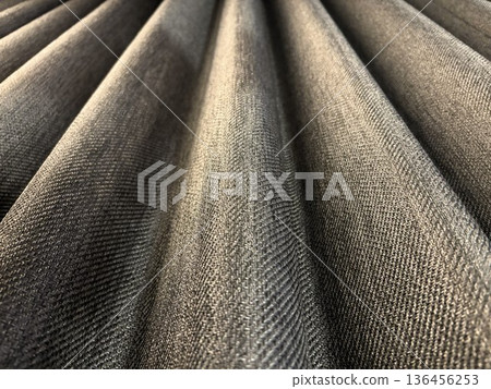 A close-up of the beautiful drape and texture of a heavy, grey blackout curtain 136456253