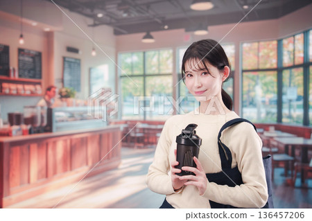 一位年輕女子拿著自己的杯子走進咖啡館。 136457206