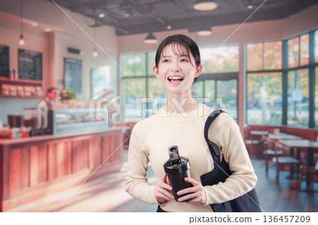 一位年輕女子拿著自己的杯子走進咖啡館。 136457209