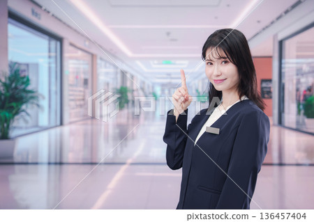 一位女員工在購物中心指引方向 一位女員工在購物中心指引方向 136457404