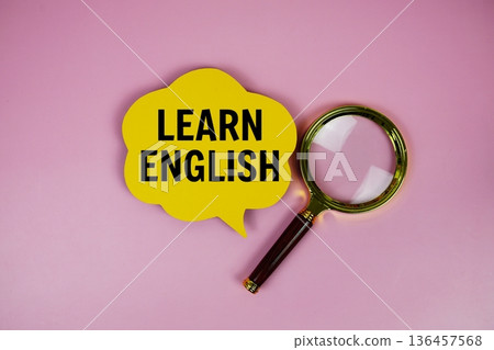Learn English text on speech bubble with magnifying glass on pink background 136457568