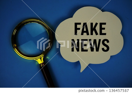Fake News text on speech bubble with magnifying glass on blue background 136457587