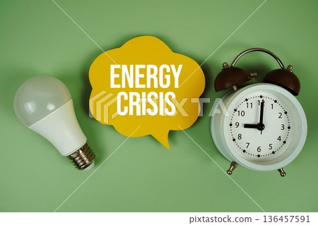 Energy Crisis text with light bulb and alarm clock on green background Energy Crisis text with light bulb and alarm clock on green background 136457591