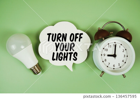 Turn Off Your Lights with light bulb and alarm clock on green background Turn Off Your Lights with light bulb and alarm clock on green background 136457595