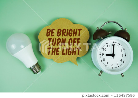 Be Bright Turn Off the Light with light bulb and alarm clock on green background 136457596