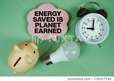 Energy Saved is Planet Earned with light bulb, piggy bank and alarm clock on green background Energy Saved is Planet Earned with light bulb, piggy bank and alarm clock on green background 136457599