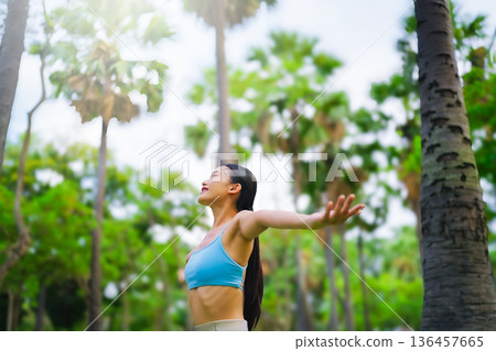 Young Asian woman relaxed breathing fresh air with trees in the background on a sunny day Young Asian woman relaxed breathing fresh air with trees in the background on a sunny day 136457665