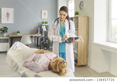 Young woman patient lying on couch in hospital and talking with doctor in medical clinic 136457719