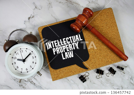 Intellectual Property Law text on speech bubble with alarm clock and wooden gavel on marble background 136457742
