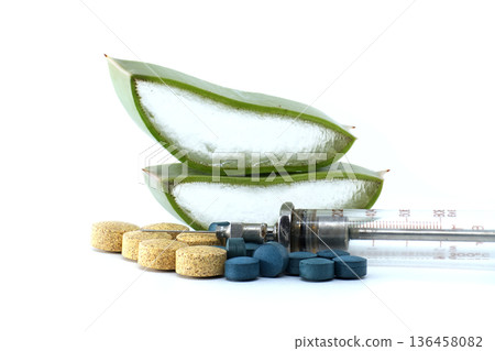 Aloe vera slices and pills with a vintage syringe on a white background 136458082