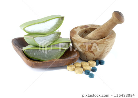 Aloe vera slices in a wooden bowl with a mortar and pestle and pills 136458084