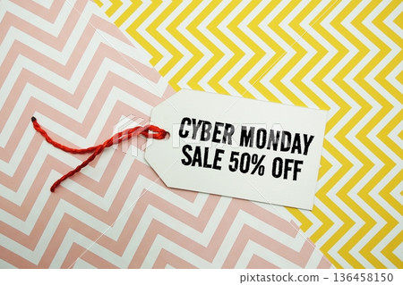 Price tag with "Cyber Monday Sale 50% Off" is placed on a colorful zigzag patterned background 136458150