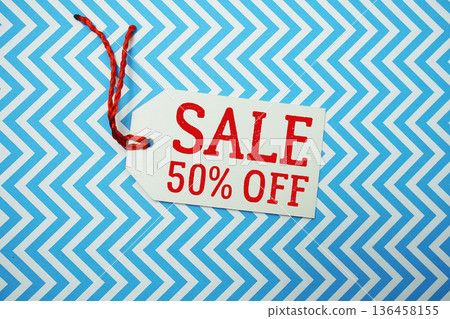 Price tag with "Sale 50% Off" is placed on a colorful zigzag patterned background, symbolizing a limited-time promotional offer Price tag with "Sale 50% Off" is placed on a colorful zigzag patterned background, symbolizing a limited-time promotional offer 136458155