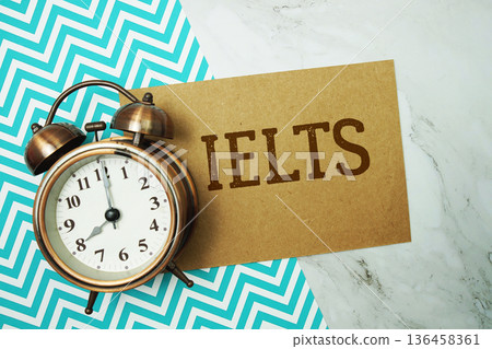 IELTS text written on paper card with alarm clock on marble background IELTS text written on paper card with alarm clock on marble background 136458361