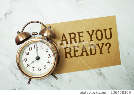 Are You Ready? text written on paper card with alarm clock on marble background Are You Ready? text written on paper card with alarm clock on marble background 136458369