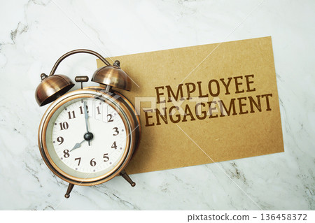 Employee Engagement text written on paper card with alarm clock on marble background Employee Engagement text written on paper card with alarm clock on marble background 136458372