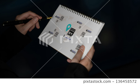 Person Holding Sketchbook with Map Symbols and Location Marker in Dark Setting for Creative Concept Development and Planning Gantry 136458572