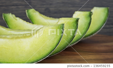 close up of a green cantaloupe slice on a piece of wooden. close up of a green cantaloupe slice on a piece of wooden. 136459235