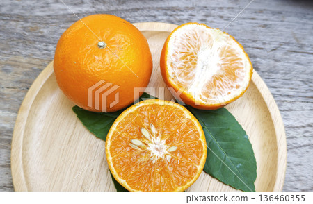 Oranges were placed on a wooden plate on the table. 136460355