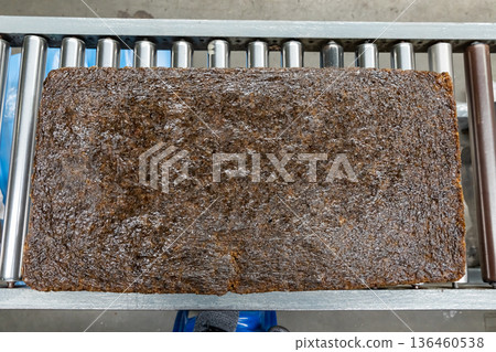 The close up image of the jagged brown natural raw rubber bales surface, lumpy solid block standard Thai rubber, in a factory. 136460538