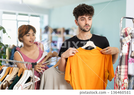 Young couple choosing dress and t-shirt in clothing store 136460581