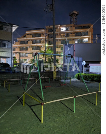 夜幕下的公園,有鞦韆,背景是公寓大樓,展現了城市住宅區的景色。 夜幕下的公園,有鞦韆,背景是公寓大樓,展現了城市住宅區的景色。 136460592