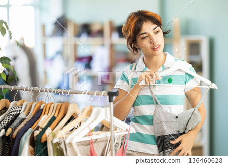 Young girl shopping for summer outfits in store Young girl shopping for summer outfits in store 136460628