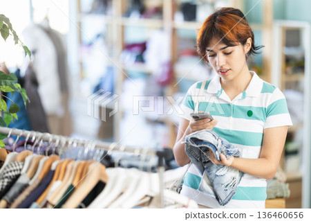 Female shopper checks quality of short by scanning QR code on label Female shopper checks quality of short by scanning QR code on label 136460656