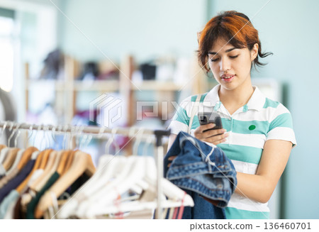 Young woman scanning qr code of jeans in store Young woman scanning qr code of jeans in store 136460701