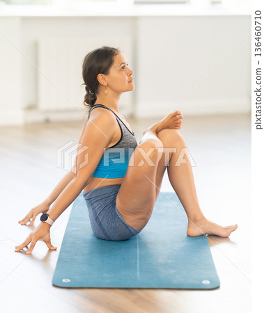 Sportive girl practicing seated pose of yoga in light room 136460710
