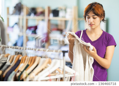 Young woman choosing warm knit sweater in clothing store Young woman choosing warm knit sweater in clothing store 136460718