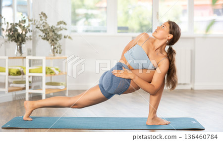 Sportive girl practicing lizard pose of yoga in light room Sportive girl practicing lizard pose of yoga in light room 136460784